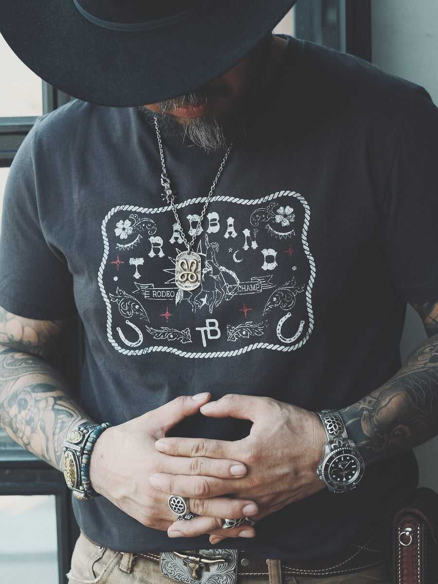 Rugged-looking man with beard and with cool Japanese style tattoos wearing a black cotton Distressed Vintage Cowboy Belt Buckle Graphic T-Shirt, 