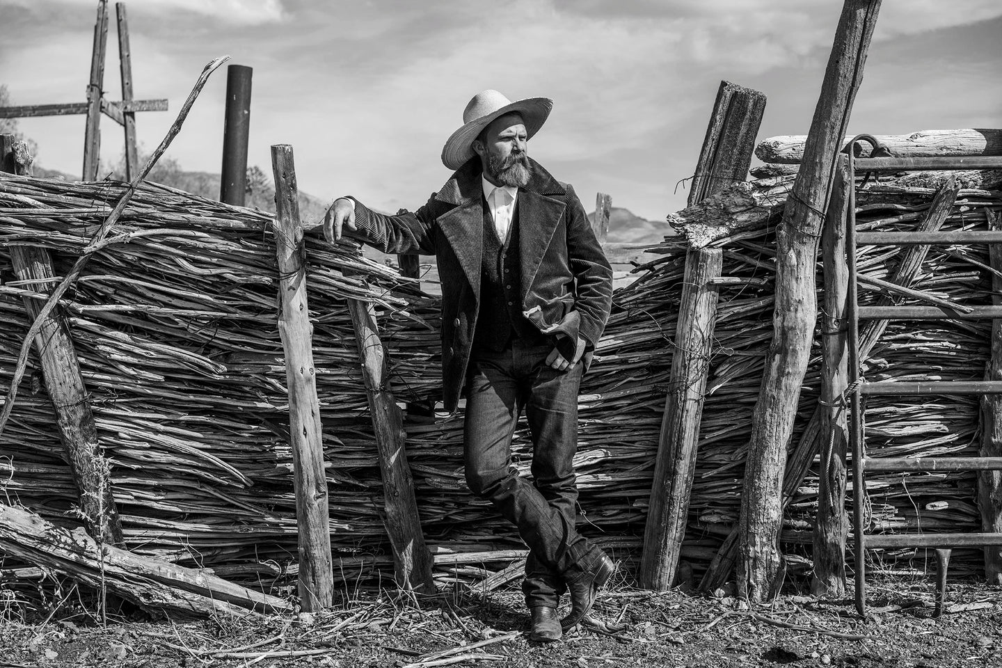 Black and white picture. A model wearing vintage inspired corduroy coat, cowboy boots, rugged blue levis jeans